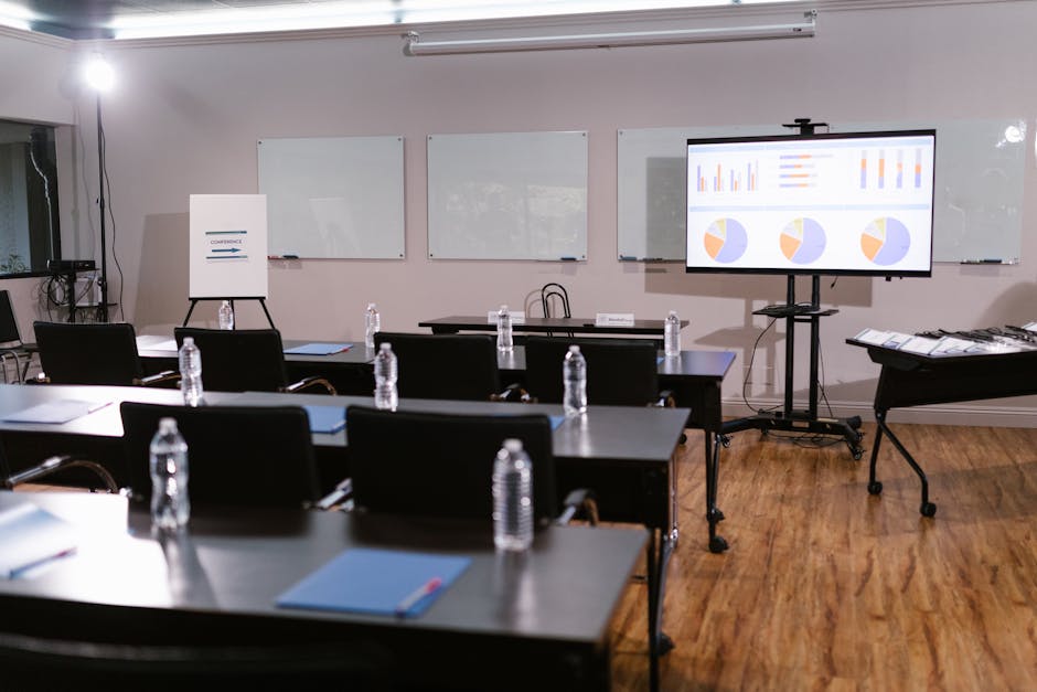Modern conference room with projector, graphs, chairs, and bottled water setup for presentation.